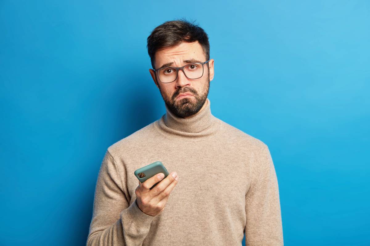 displeased-bearded-guy-smirks-face-uses-modern-cellphone-has-sad-expression-wears-transparent-glasses-and-jumper (1)